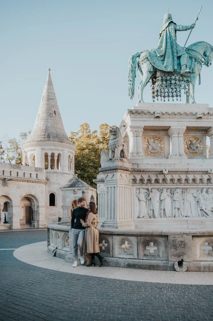 Budapest couple photoshoot: a portrait beside the equestrian statue The couple sitting apart on the stone base of a bronze equestrian statue beside Fisherman’s Bastion during a couple photoshoot in Budapest.