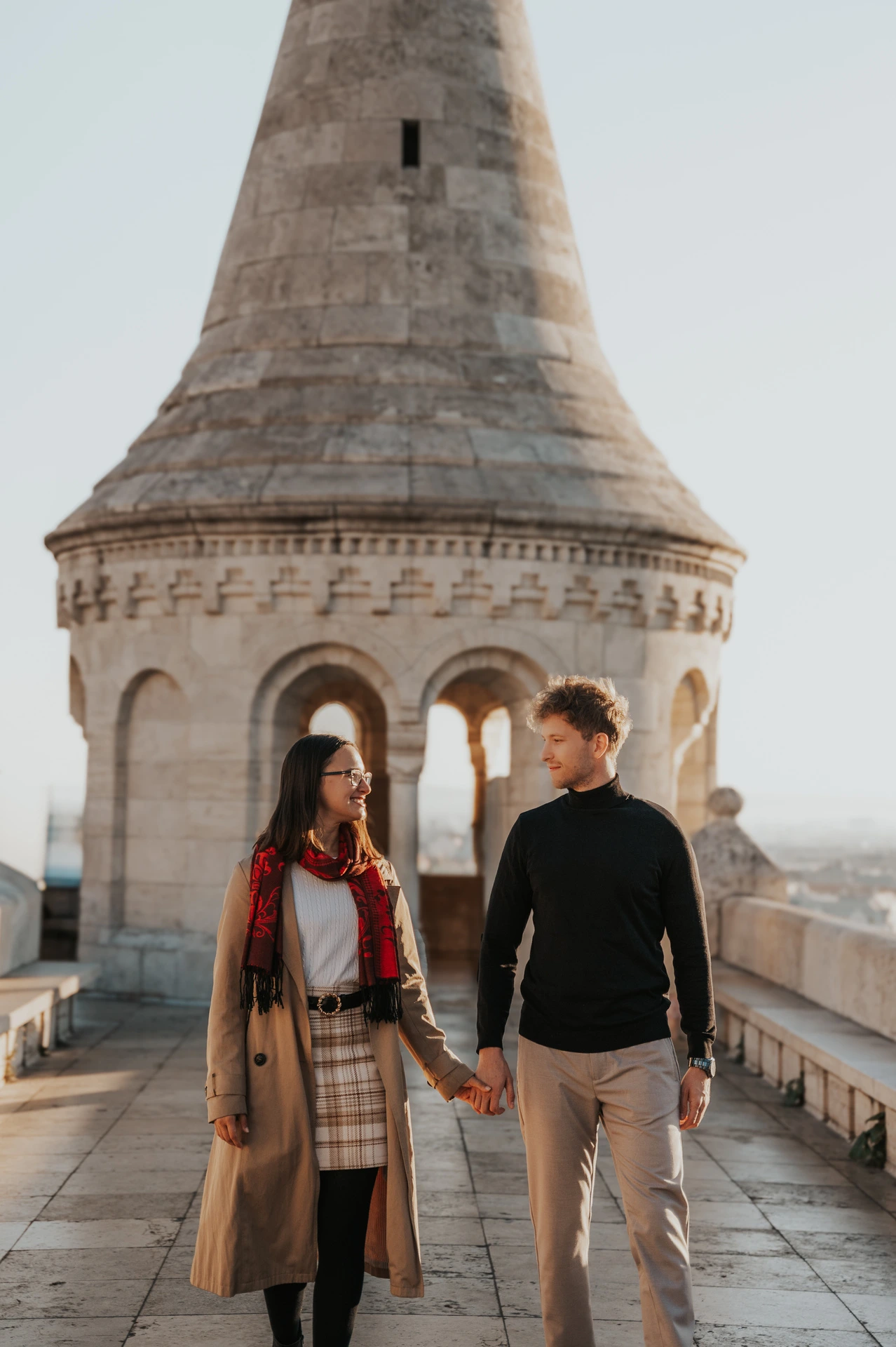 A closer view of the couple walking together in front of Fisherman’s Bastion’s pointed tower during a couple photoshoot in Budapest.