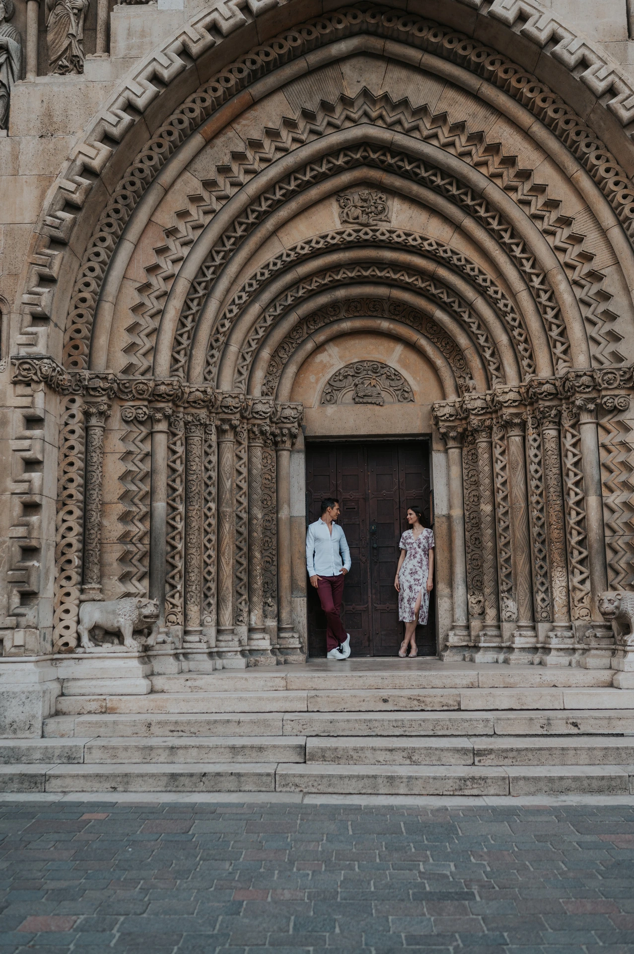 The couple standing beneath the deeply carved arched doorway at Vajdahunyad Castle during their couple photoshoot in Budapest.
