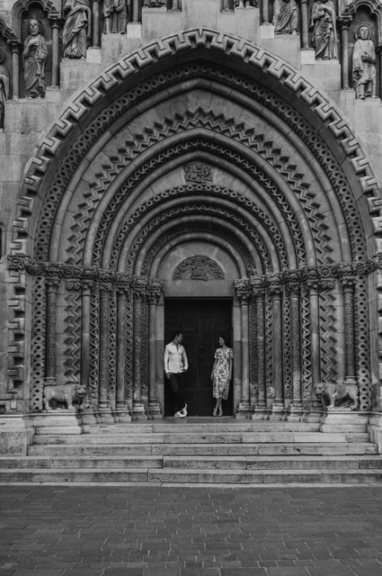 Castle doorway in black and white at a Budapest couple photoshoot Black-and-white portrait of the couple beneath the carved stone arches at Vajdahunyad Castle during their couple photoshoot in Budapest.