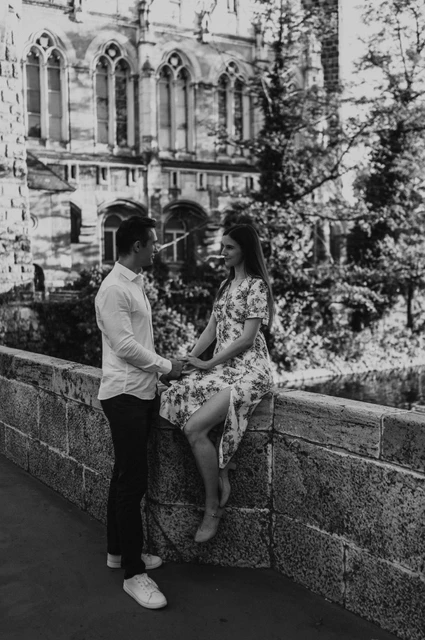 A palace portrait in black and white at a Budapest couple photoshoot Black-and-white portrait of the couple beside a low stone wall with the ornate palace façade of Vajdahunyad Castle behind them during their couple photoshoot in Budapest.
