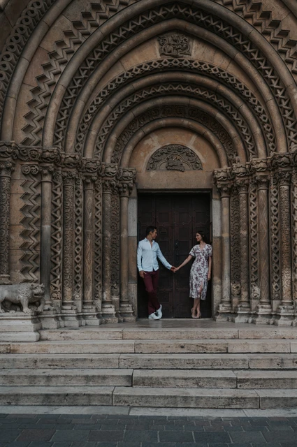 The couple holding hands on the steps beneath Vajdahunyad Castle’s ornate doorway during their couple photoshoot in Budapest.