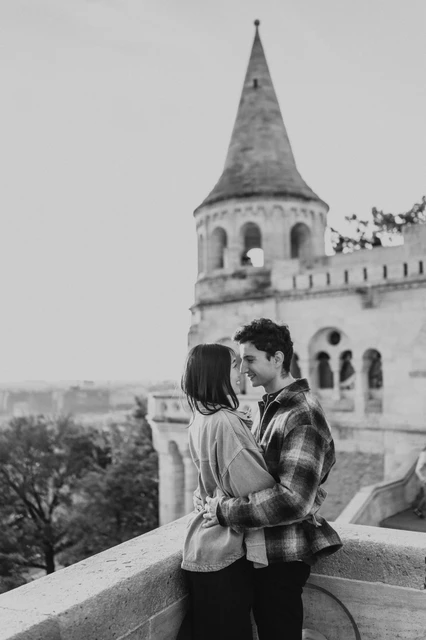 Budapest engagement photoshoot: a black-and-white kiss on the terrace Black-and-white portrait of the couple kissing beside the terrace wall, with the Bastion tower behind them during their Budapest engagement photoshoot.