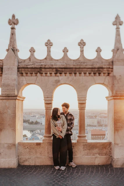 Budapest engagement photoshoot: a closer embrace beneath the central arch A closer view of the couple holding each other beneath the arched openings at Fisherman’s Bastion during their Budapest engagement photoshoot.