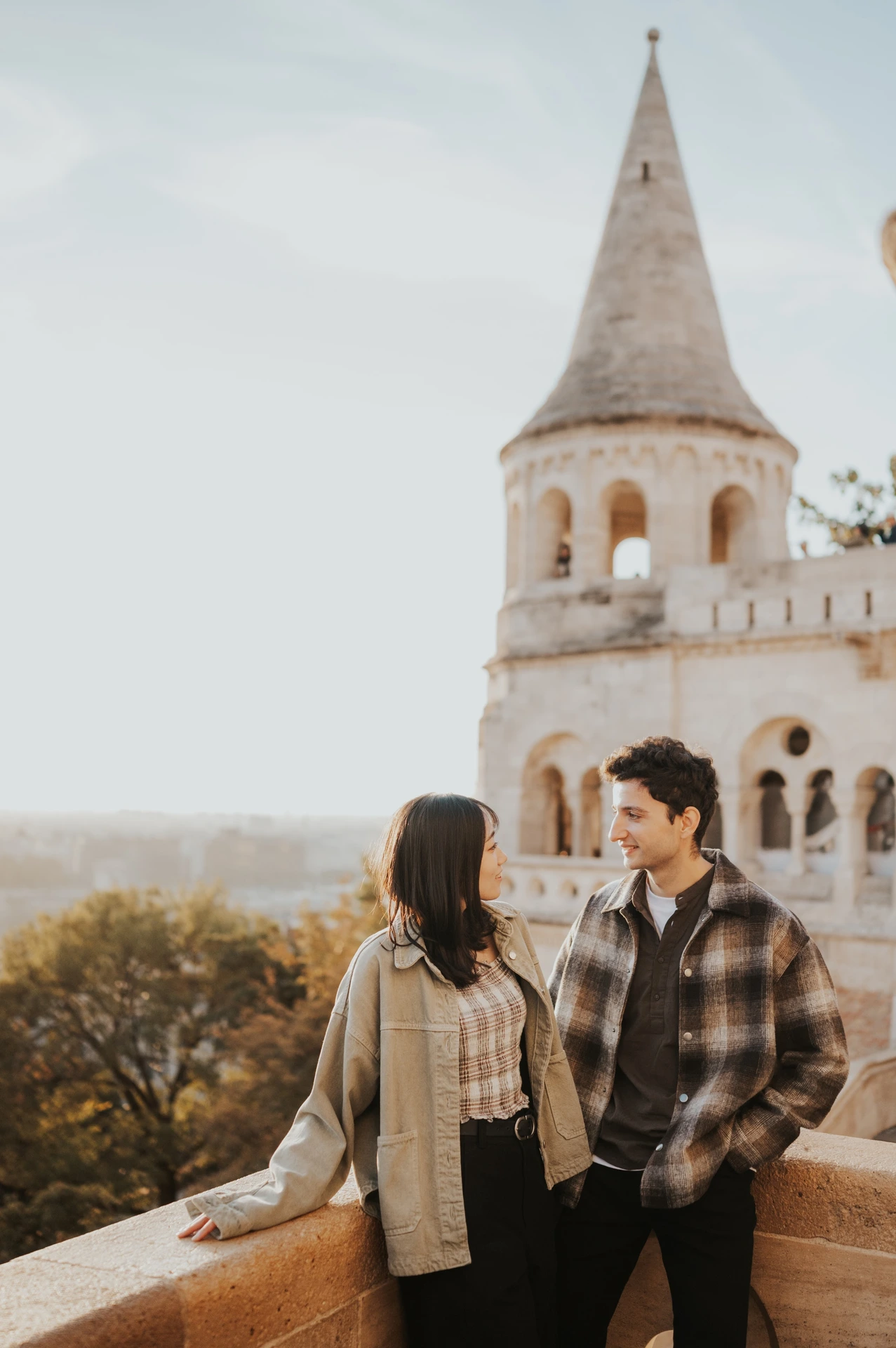 A closer view of the couple looking towards each other on the Bastion terrace, with the pale tower softly behind them during their Budapest engagement photoshoot.