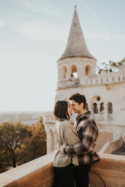 Budapest engagement photoshoot: a kiss beside the curved stone balustrade The couple kissing beside the curved stone balustrade at Fisherman’s Bastion, with the pointed tower in the backdrop during their Budapest engagement photoshoot.