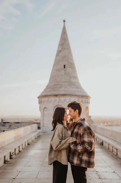 Budapest engagement photoshoot: a kiss on the Bastion walkway The couple kissing on the stone walkway at Fisherman’s Bastion, with the pointed tower behind them during their Budapest engagement photoshoot.