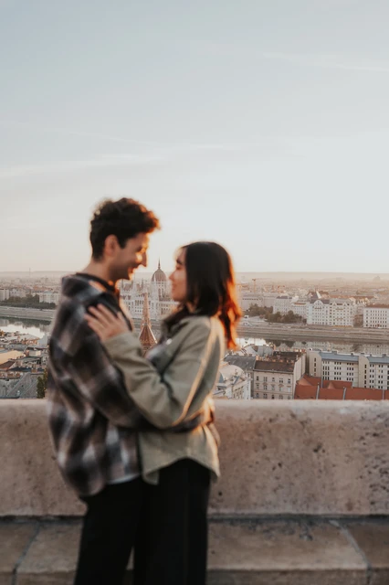 Budapest engagement photoshoot: a quiet moment in the morning light The couple looking towards each other in a gentle embrace beside the Bastion terrace wall, their faces lit by the morning sun during their Budapest engagement photoshoot.