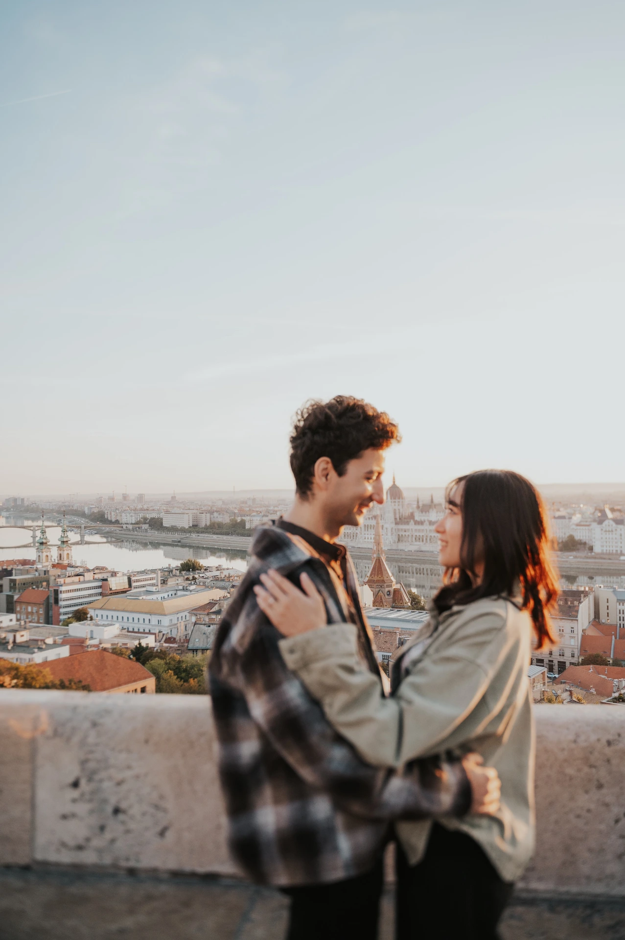 The couple standing close together beside the stone terrace wall at Fisherman’s Bastion, with Budapest in the background during their Budapest engagement photoshoot.