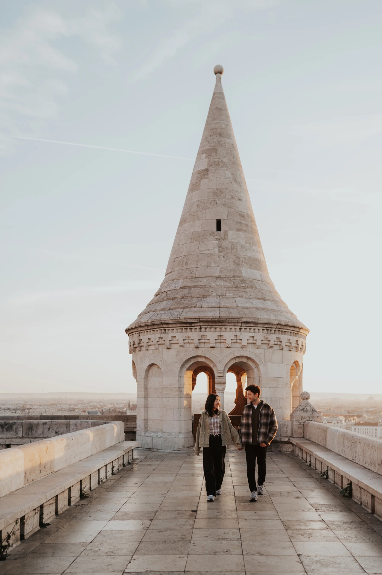 The couple walking hand in hand towards the camera along the balustraded walkway at Fisherman’s Bastion during their Budapest engagement photoshoot.