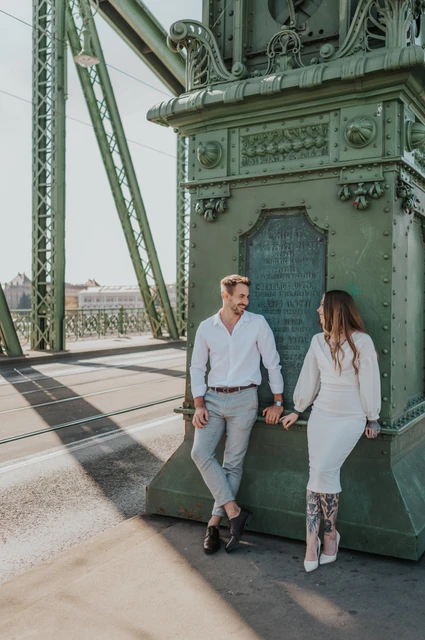 Hand in hand beside the green lamp-post | Budapest engagement photoshoot The couple holding hands beside the large green lamp-post base on Liberty Bridge during their engagement photoshoot in Budapest.