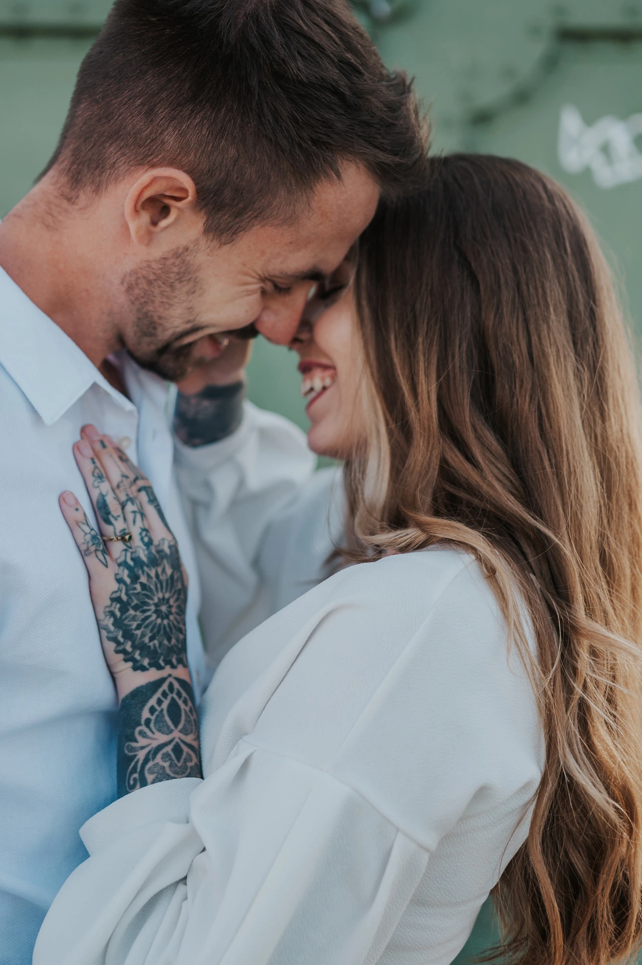 A close portrait of the couple smiling with their foreheads together against green bridge ironwork during their engagement photoshoot in Budapest.