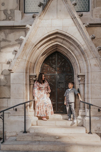 A mother and her nine-year-old son standing on the steps in front of a carved Gothic doorway during their family photoshoot in Budapest.