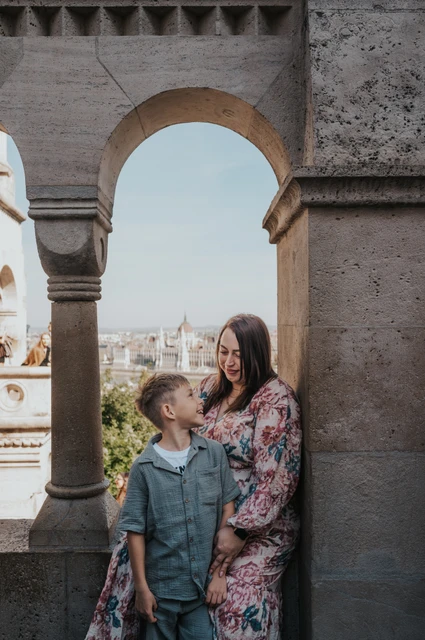 A closer portrait of a mother and son looking at one another beneath the pale stone arches of Fisherman’s Bastion during their family photoshoot in Budapest.