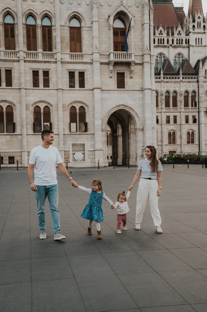 Budapest family photoshoot exploring Parliament Square together The parents guiding their children by the hand across the square during their Budapest family photoshoot near Parliament.
