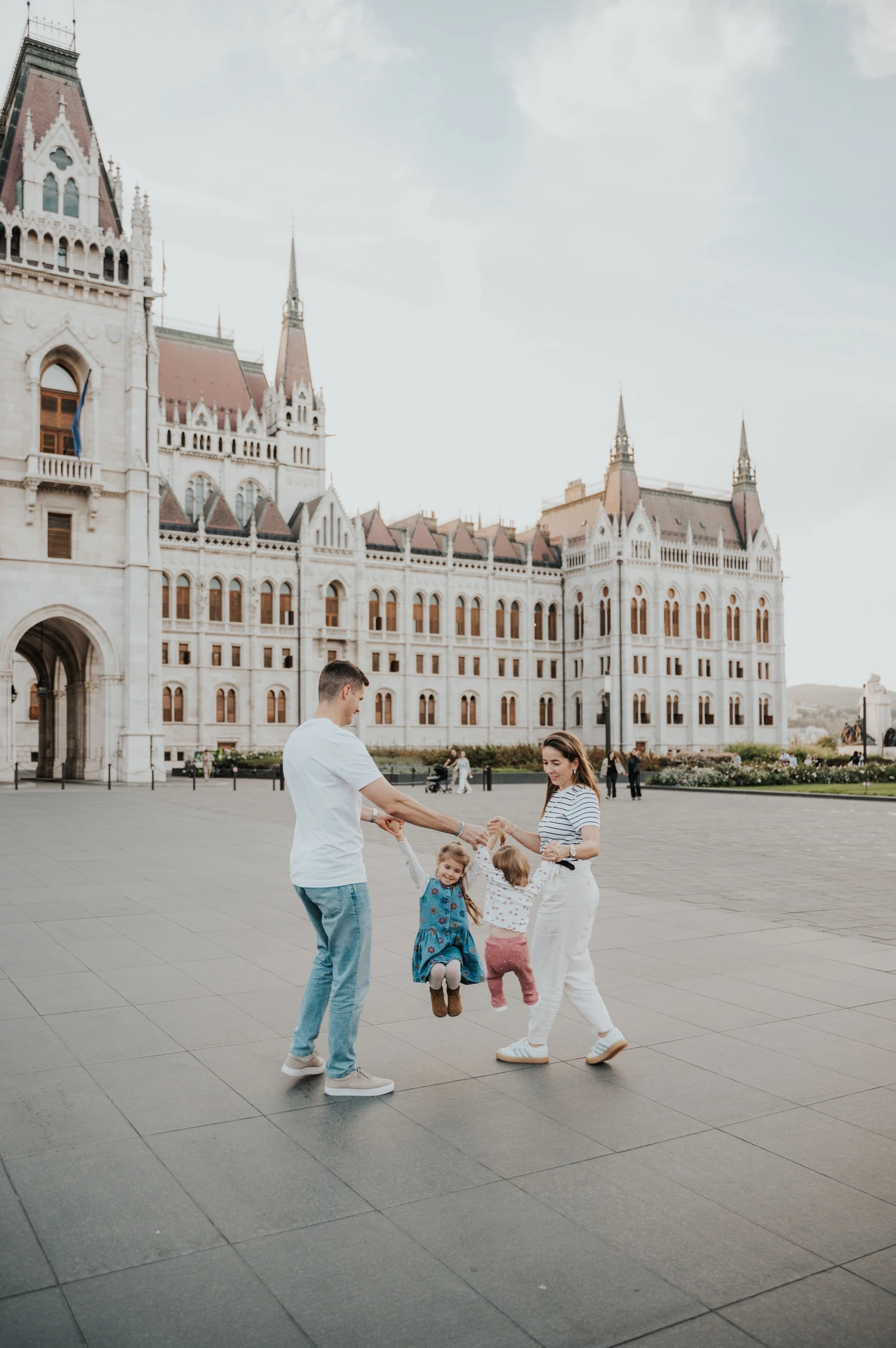 Playful family photoshoot in Budapest outside Parliament The parents and children sharing a playful moment while holding hands during their Budapest family photoshoot in front of Parliament.
