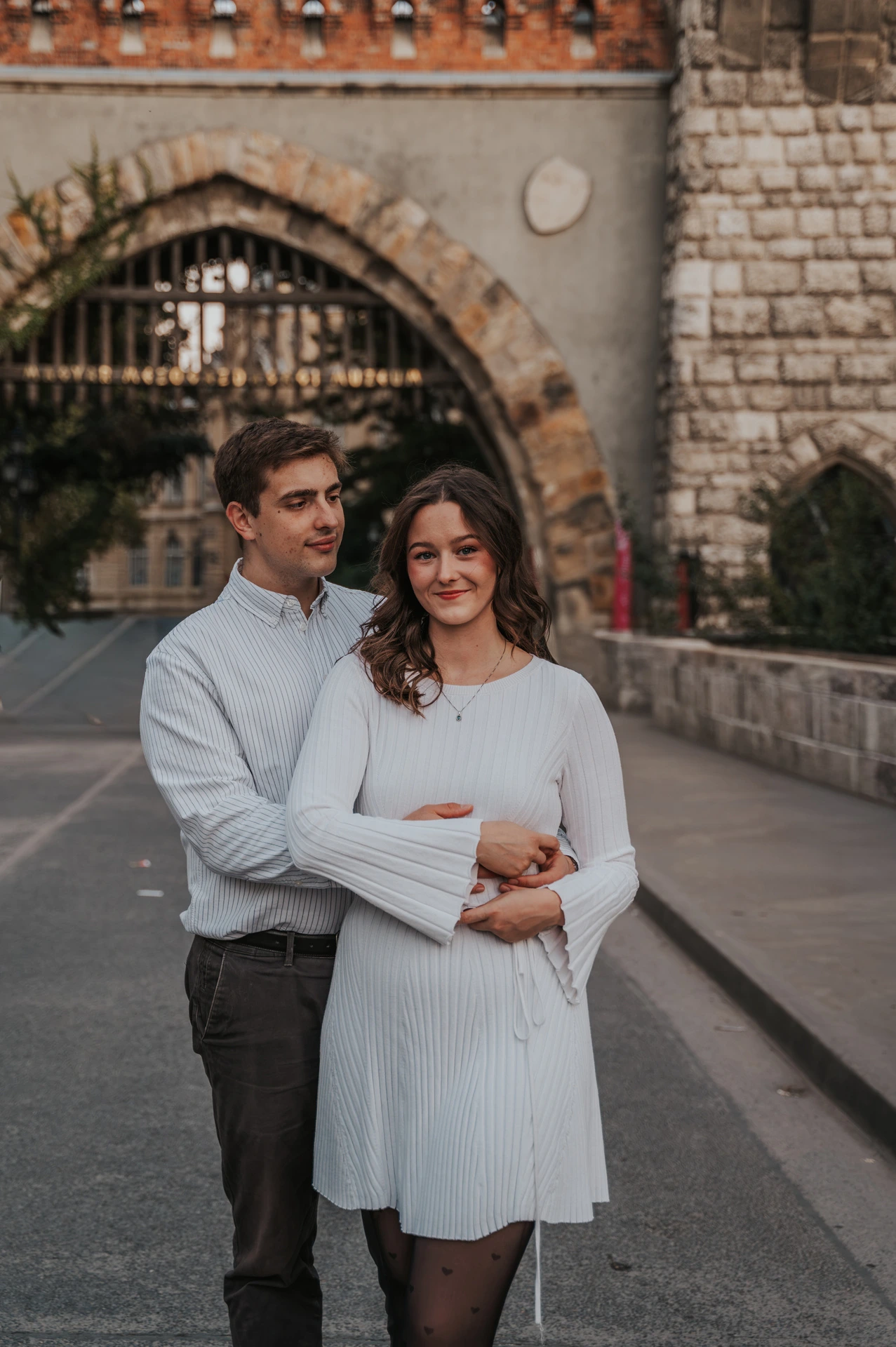 A close portrait of the smiling couple embracing in front of Vajdahunyad Castle’s arched gateway during their anniversary photoshoot in Budapest.