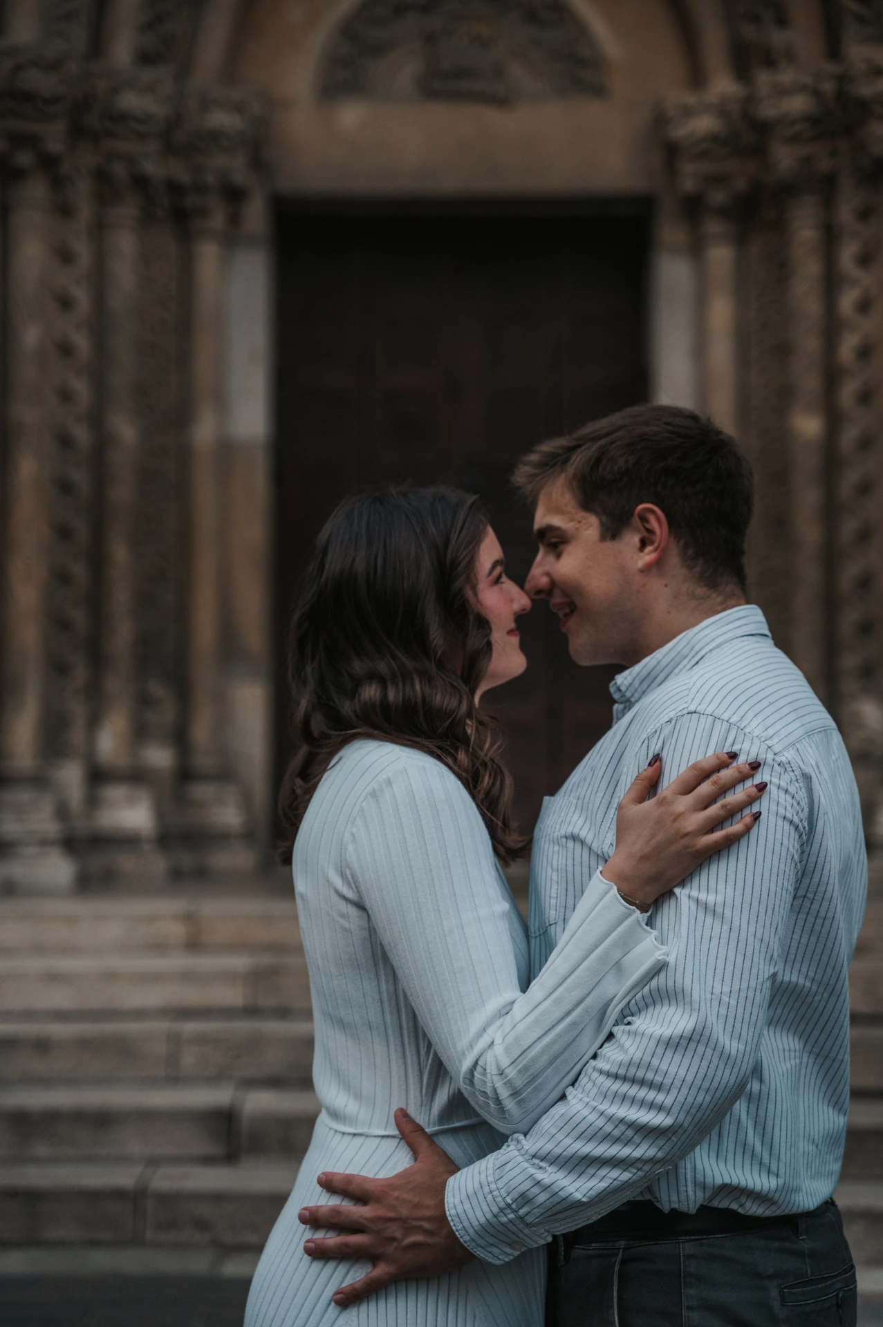 A close portrait of the couple leaning towards one another with Vajdahunyad Castle’s doorway softly blurred behind them during their anniversary photoshoot in Budapest.