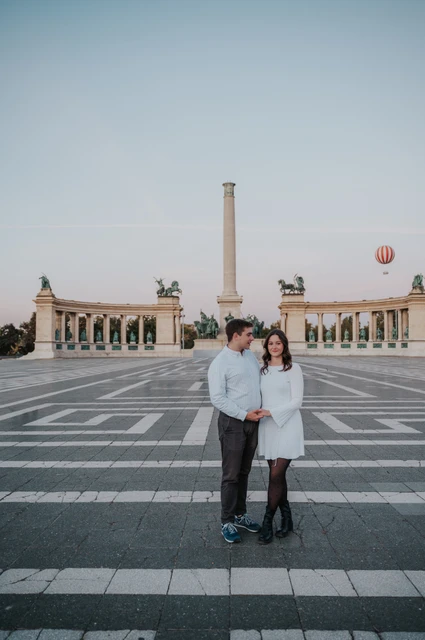An anniversary portrait at Heroes’ Square at a Budapest anniversary photoshoot A full-length portrait of the couple at Heroes’ Square with the central column and curved colonnade behind them during their anniversary photoshoot in Budapest.