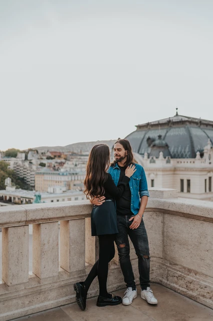 A quiet corner on the castle terrace at a Budapest couple photoshoot The couple standing close in the corner of a stone terrace at Buda Castle with city rooftops behind them during their couple photoshoot in Budapest.