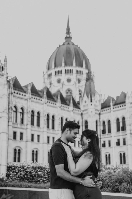 A Budapest couple photoshoot embrace by Parliament in black and white Black-and-white portrait of the couple embracing in front of Parliament’s dome during their couple photoshoot in Budapest.