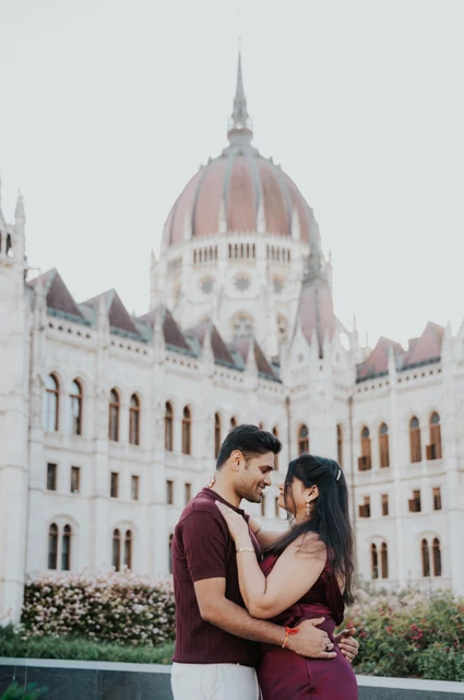 The couple embracing with Parliament’s dome and pointed stone spires behind them during their Budapest couple photoshoot.