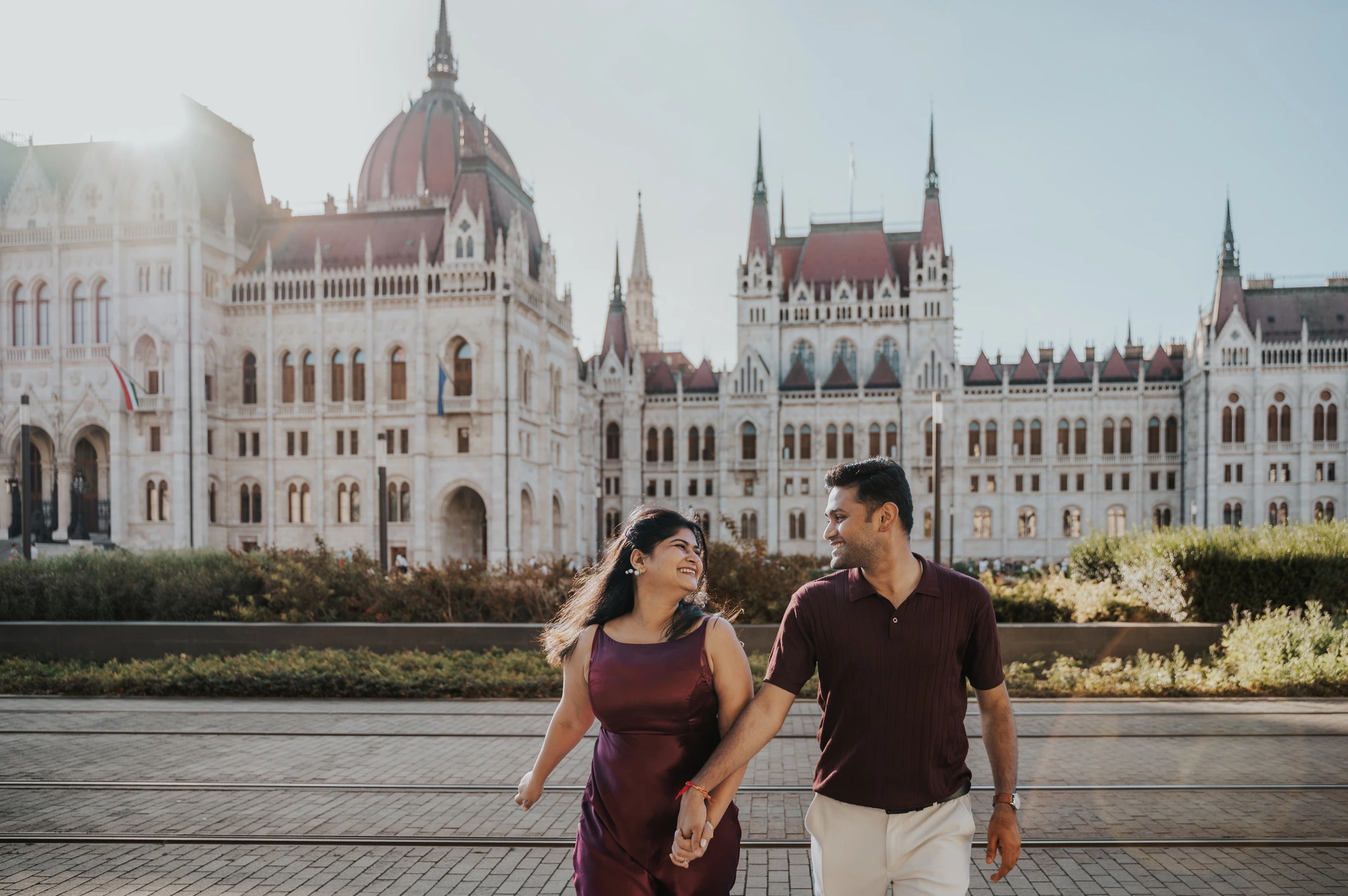 Laughter by Parliament at a Budapest couple photoshoot The couple looking at each other and laughing as they walk in front of Parliament during their Budapest couple photoshoot.