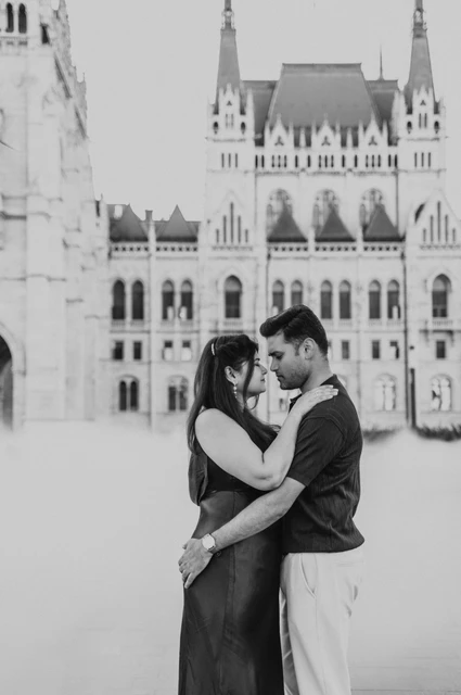 A Budapest couple photoshoot embrace in mist and black and white Black-and-white portrait of the couple holding one another beside Parliament with soft mist around them during their Budapest couple photoshoot.