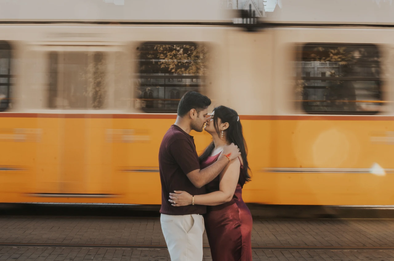 A Budapest couple photoshoot with a passing yellow tram The couple embracing while a yellow tram passes behind them during their couple photoshoot in Budapest.
