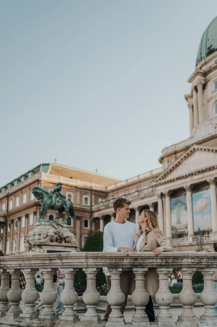 A portrait beneath the palace dome at a Budapest couple photoshoot A closer portrait of the couple leaning on a stone balustrade beneath Buda Castle’s green dome during their couple photoshoot in Budapest.