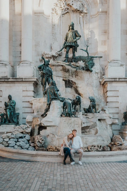 A little time beside the sculpted fountain at a Budapest couple photoshoot The couple sitting together at the base of Buda Castle’s large sculpted fountain during their couple photoshoot in Budapest.