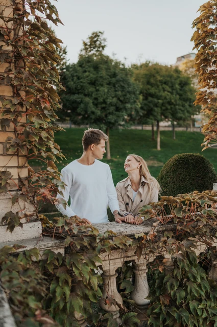 A leafy corner in the castle gardens at a Budapest couple photoshoot The couple looking at one another beside an ivy-covered stone railing at Castle Garden Bazaar during their couple photoshoot in Budapest.