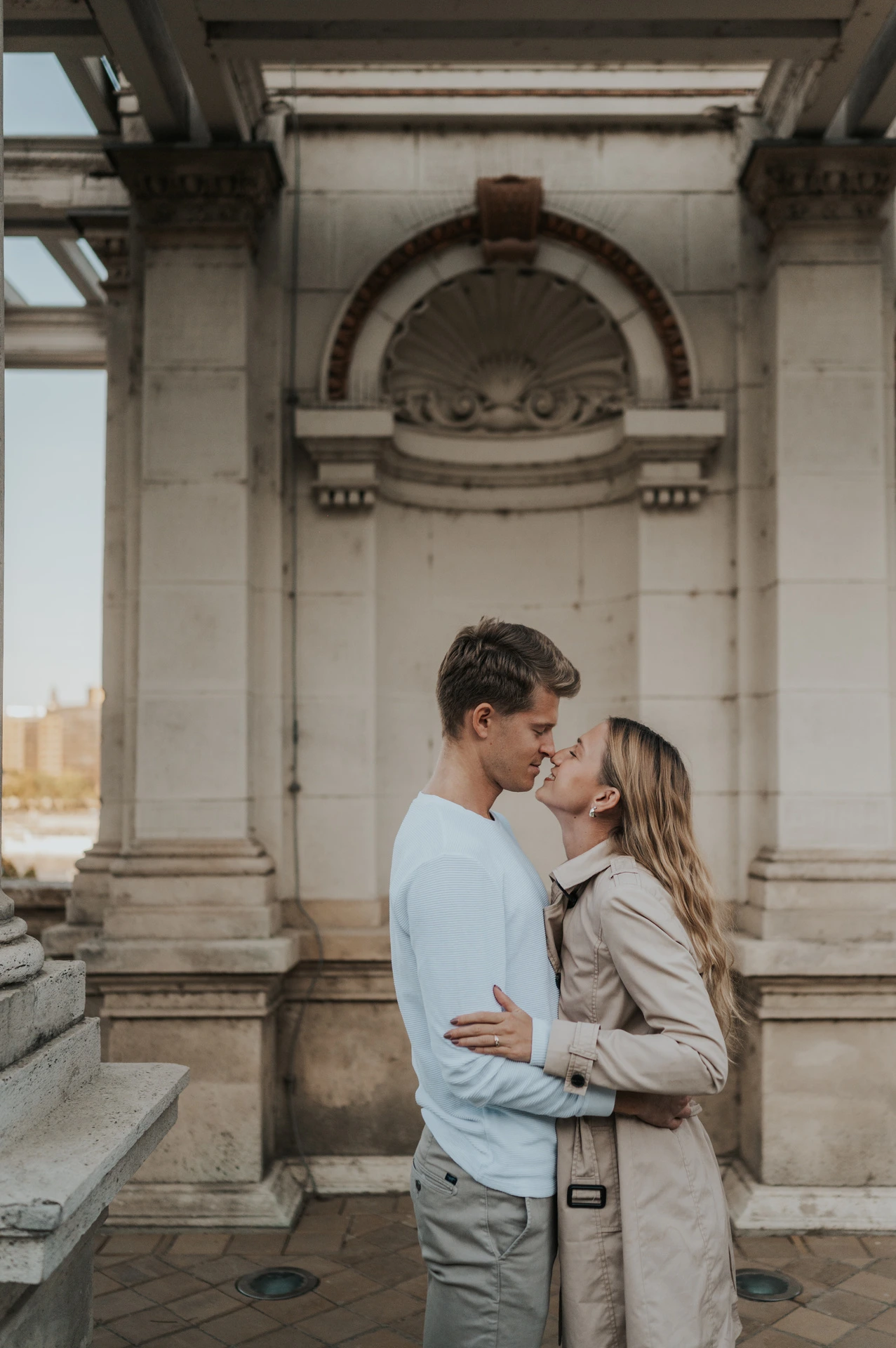A close portrait of the couple embracing beneath a carved arch at Castle Garden Bazaar’s pavilion during their couple photoshoot in Budapest.