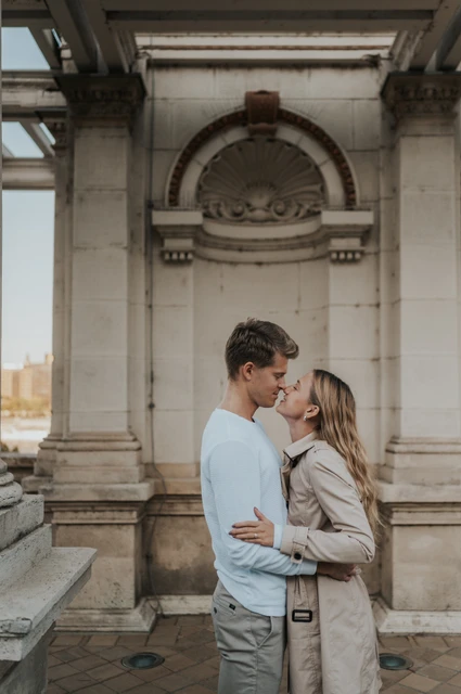A close embrace beneath the carved arch at a Budapest couple photoshoot A close portrait of the couple embracing beneath a carved arch at Castle Garden Bazaar’s pavilion during their couple photoshoot in Budapest.
