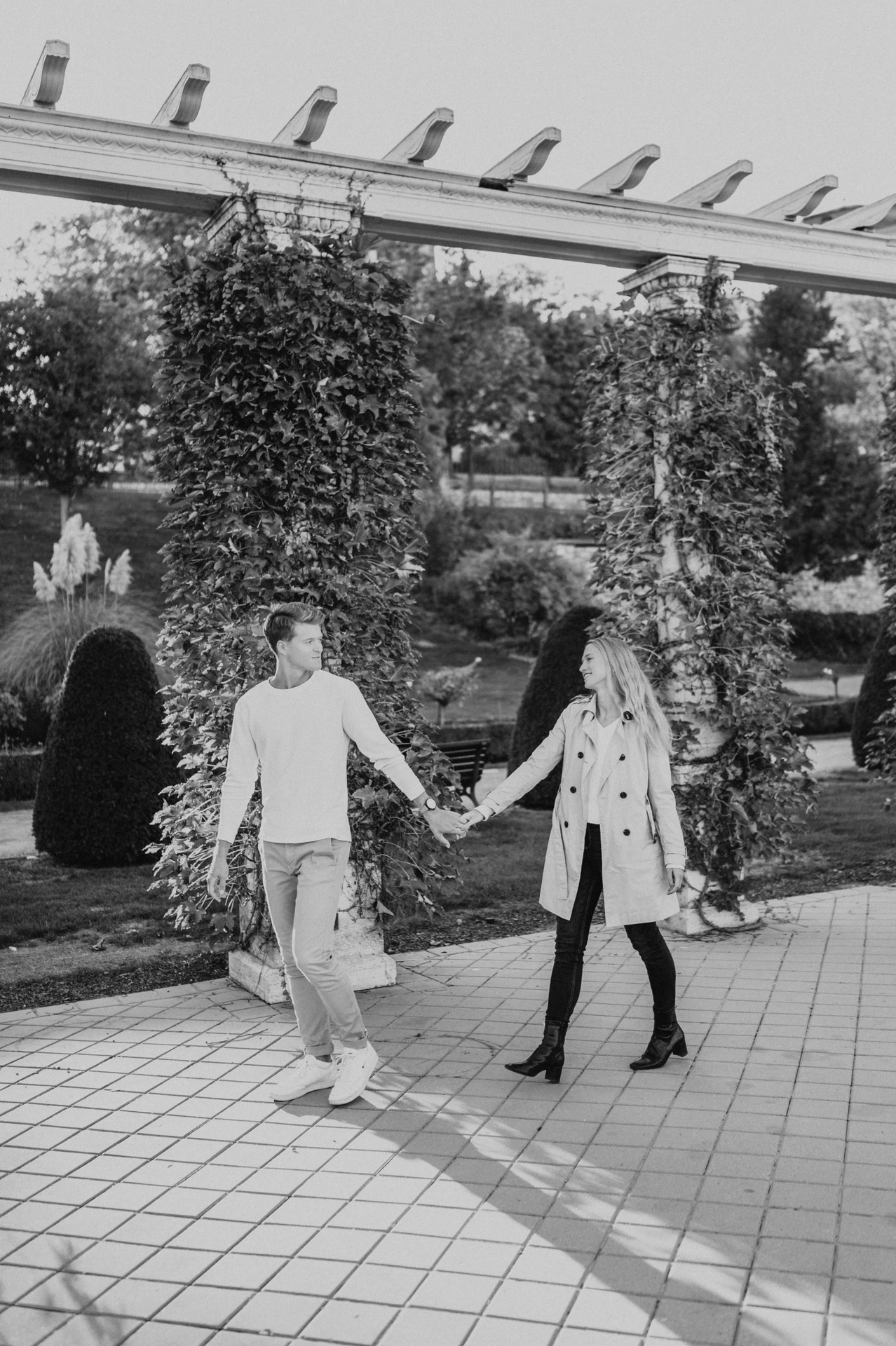 Black-and-white portrait of the couple walking beneath the pergola at Castle Garden Bazaar during their couple photoshoot in Budapest.