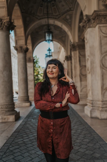 Budapest solo photoshoot: a close portrait in the Opera arcade A close portrait of the woman touching her earring beneath the Opera’s stone arches during a solo photoshoot in Budapest.