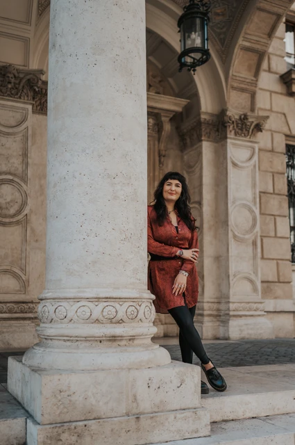 Budapest solo photoshoot: beneath the Opera’s carved arches The woman leaning against a carved column beneath the Opera’s stone arches during a solo photoshoot in Budapest.