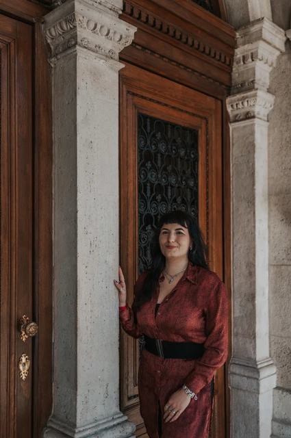 Budapest solo photoshoot: a close portrait at the Opera doorway A closer portrait of the woman in a red dress at the Opera’s ornate wooden doorway during a solo photoshoot in Budapest.