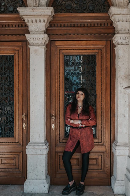 Budapest solo photoshoot: a smile framed by the Opera’s wooden doors The woman smiling beneath the ornate panels of the Opera’s wooden doors during a solo photoshoot in Budapest.