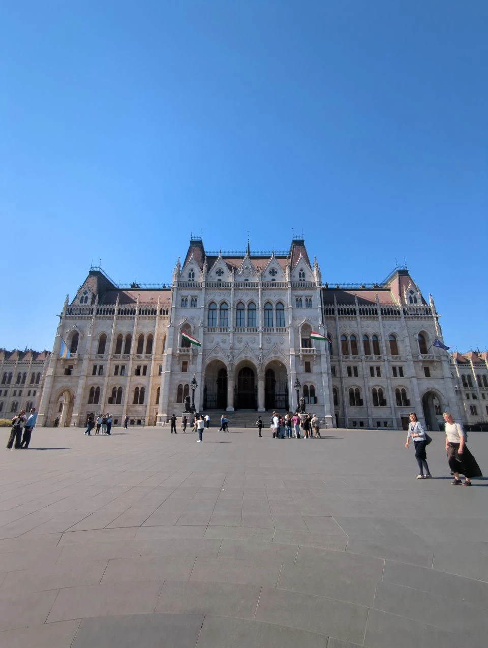 Fachada del Parlamento húngaro hacia la plaza con visitantes delante Fachada del Parlamento húngaro hacia la plaza con visitantes delante