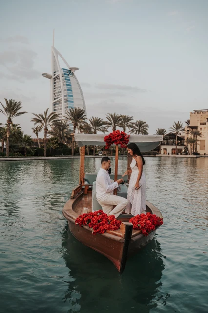 A man kneels on a decorated abra in Dubai while proposing beside floral arrangements during a luxury proposal photoshoot.