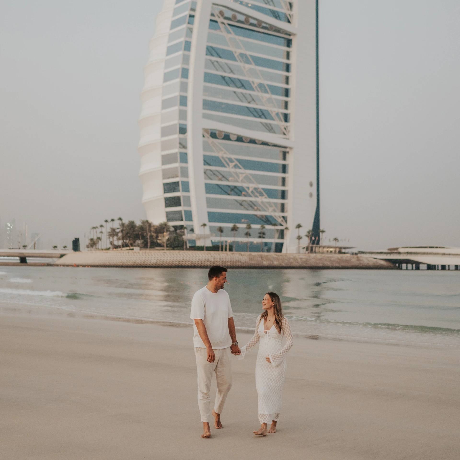 Full-body maternity couple on Dubai beach with Burj Al Arab visible