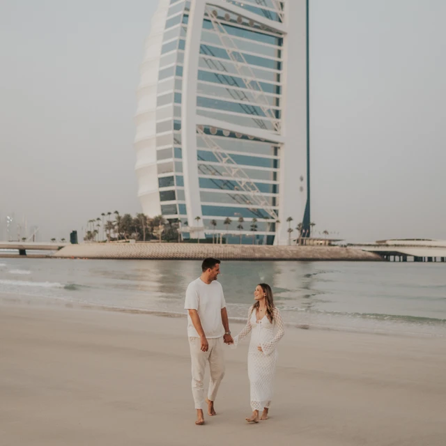 Full-body maternity couple on Dubai beach with Burj Al Arab visible
