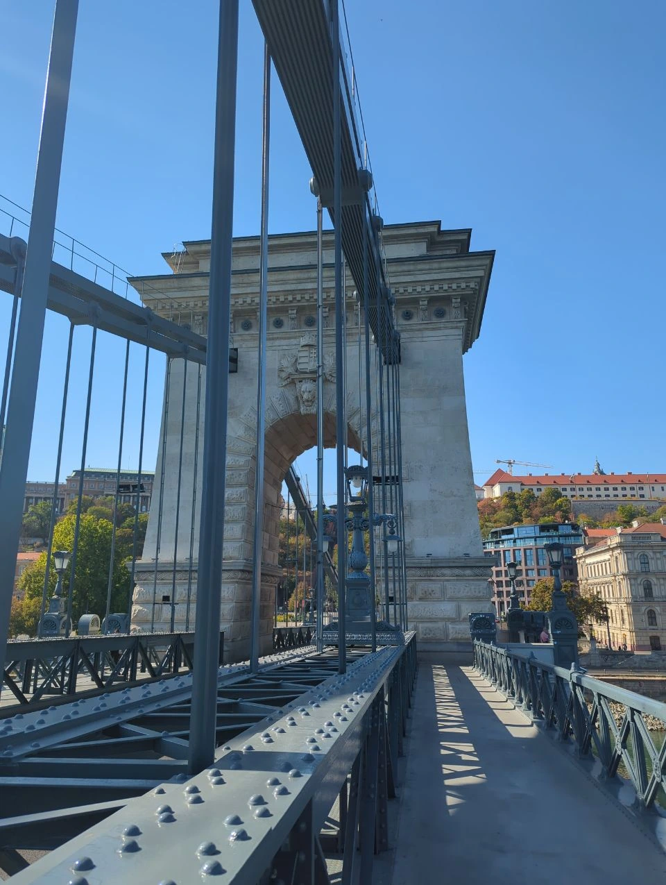 Chain Bridge ironwork and pedestrian path in Budapest Chain Bridge pedestrian walkway and stone tower framed by iron suspension members