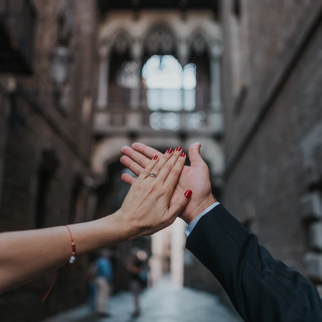 A close-up of two hands displays an engagement ring beneath Pont del Bisbe in Barcelona’s Gothic Quarter during a Barcelona engagement photoshoot.