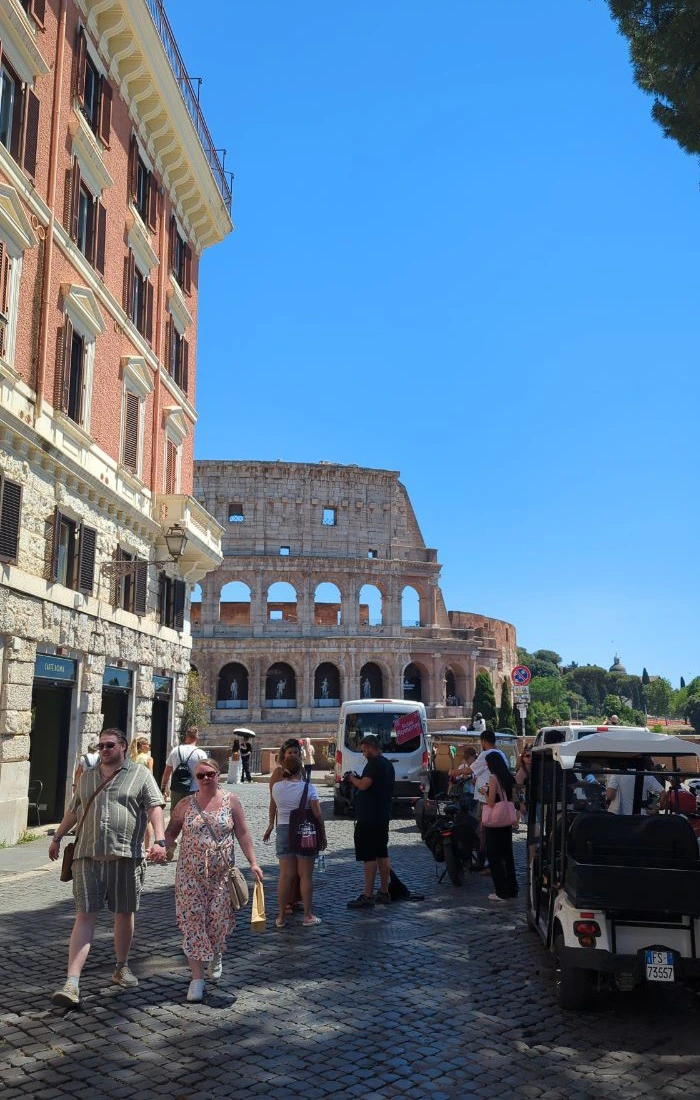 Visitors walk along a cobbled Rome street toward the Colosseum, illustrating a lively route after choosing a proposal location.