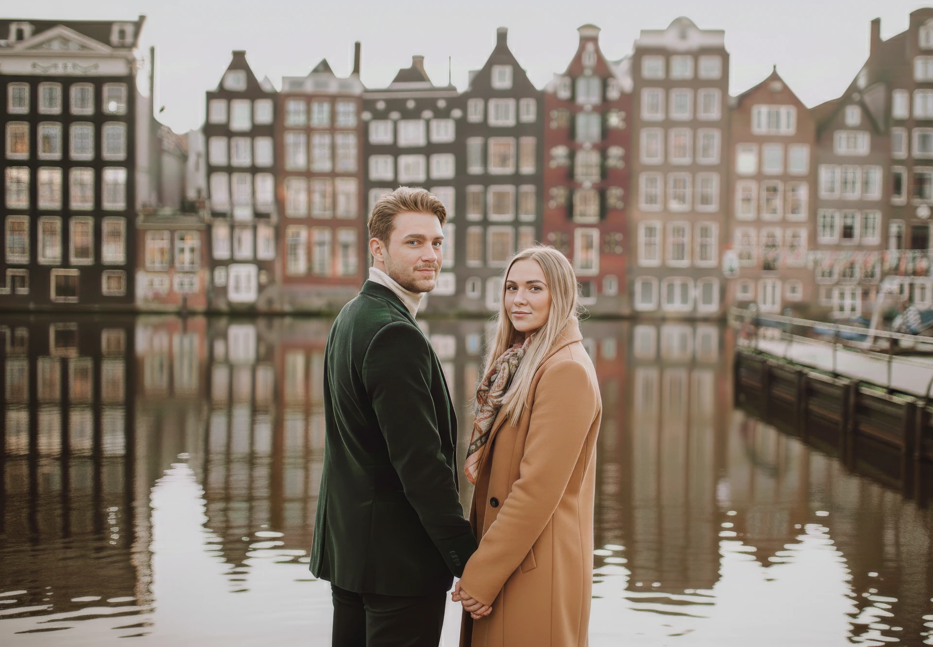 Couple at the Damrak waterfront with Amsterdam gabled houses