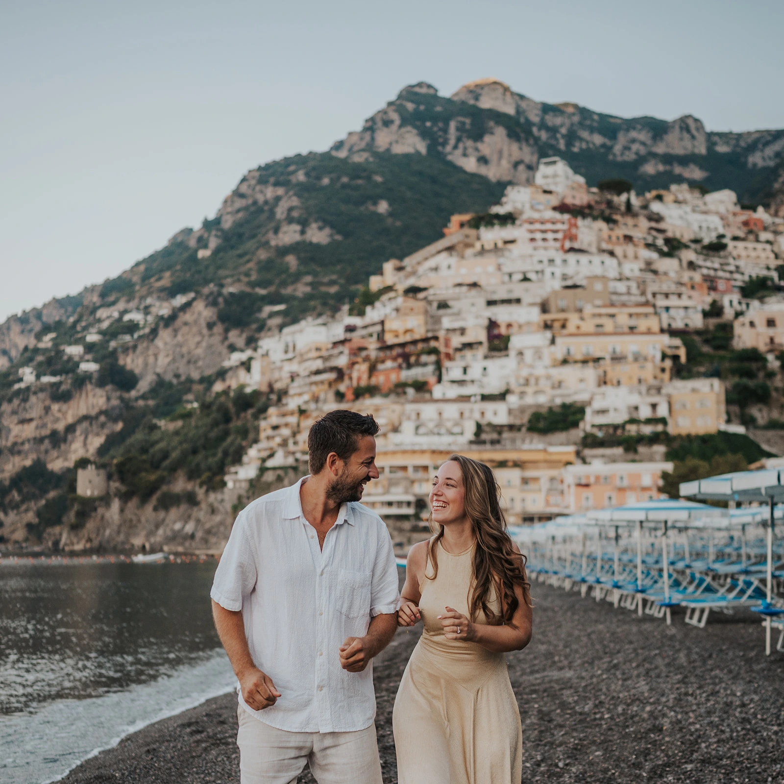 Couple on Positano beach with colourful hillside houses behind them