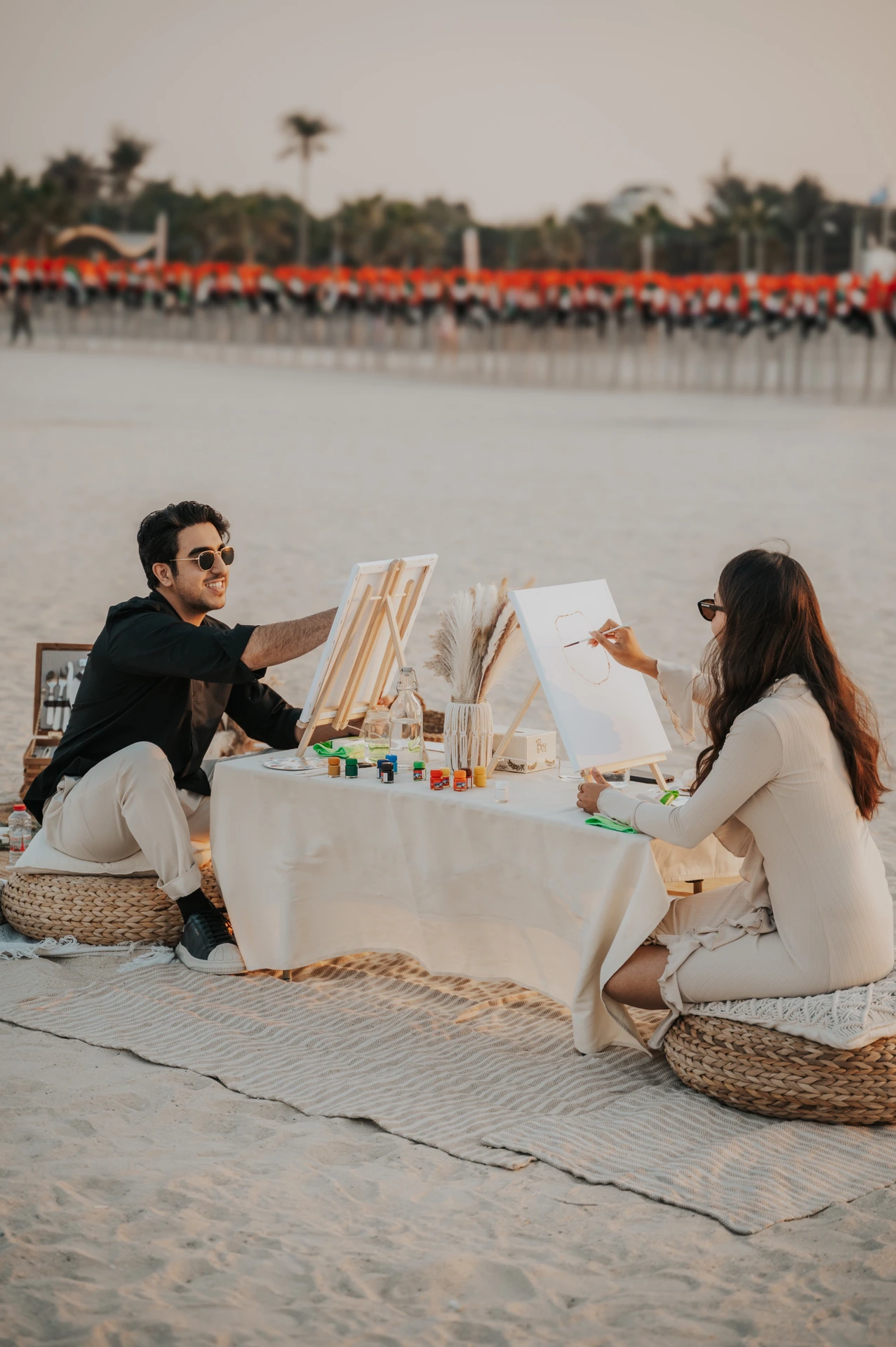 Dubai Couple Photoshoot - creative beach date A couple poses with painting props on Dubai beach during a couple photoshoot, creating playful date-style storytelling with pastel tones and sea light.
