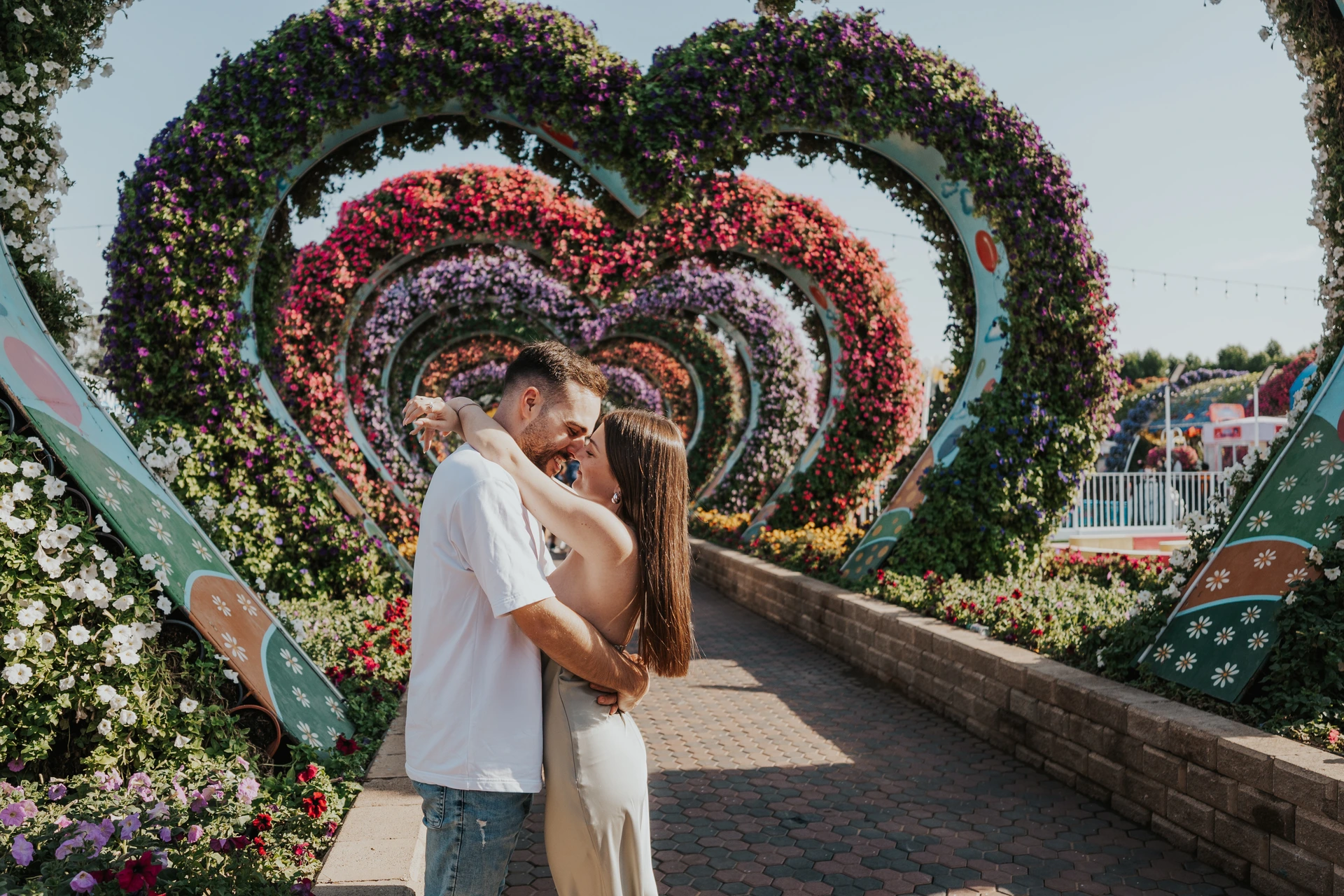 A couple poses in front of floral heart installations at Dubai Miracle Garden.